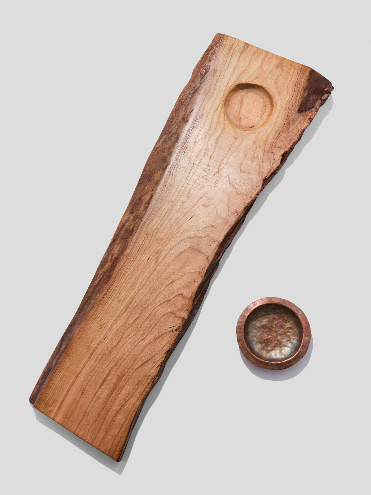  live-edge cherry wood bath tray with a hand-hammered copper ashtray next to it
