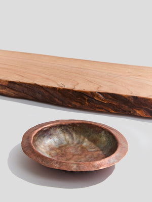  close up of live-edge cherry wood bath tray and a hand-hammered copper ashtray