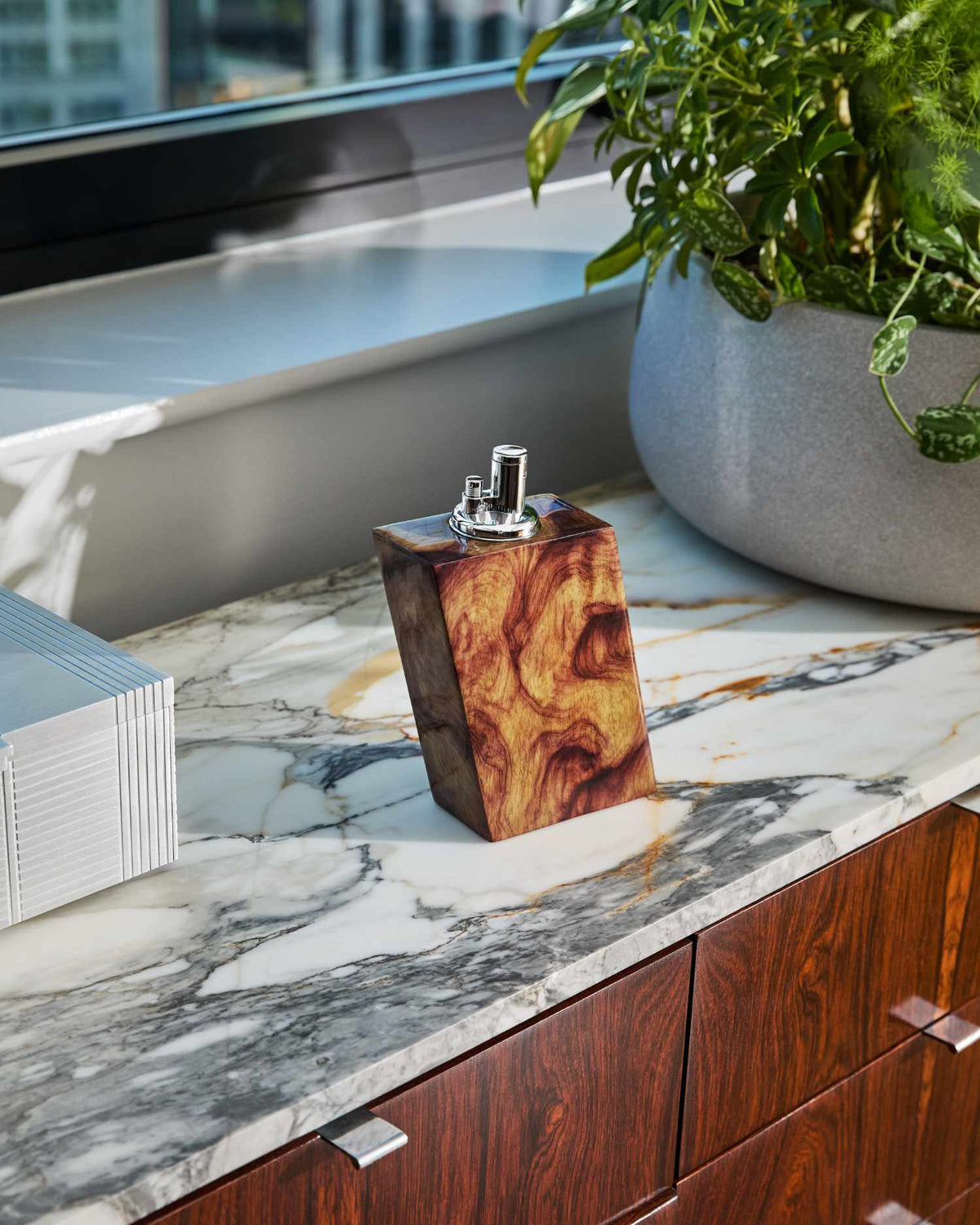 Judd wooden lighter on a marble countertop with a plant in the background